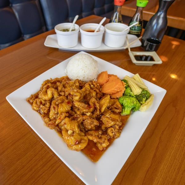 A Thai Spice Lees Summit dish with orange chicken, white rice, broccoli, baby corn, and carrots.